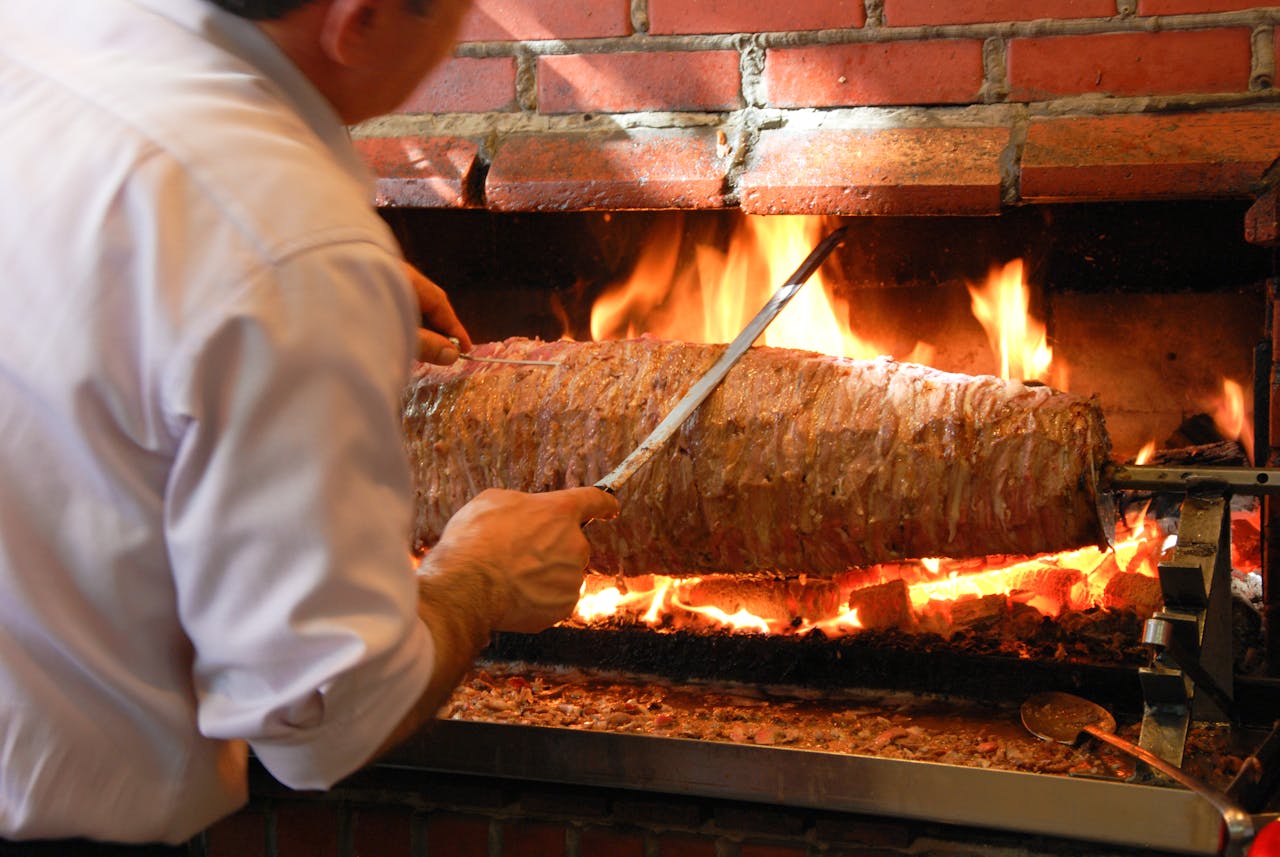 A chef preparing traditional Turkish doner kebab in Istanbul using an open flame grill.